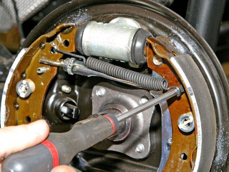 Замена задних тормозных колодок на автомобиле Рено Логан первого поколения с учетом особенностей снятия регулятора зазоров с рычагом, верхней и нижней пружин
